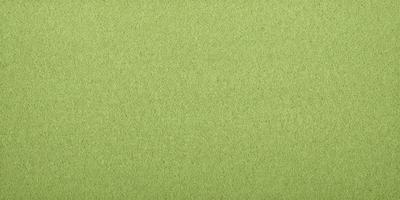 The primary subject of the image is a large, green, textured surface. The setting is a plain, empty room with no other objects or people visible. The visual style is a close-up of the green surface, which appears to be a textured fabric or a wallpaper with a green pattern. The colors and mood of the image are predominantly green, creating a calm and serene atmosphere.