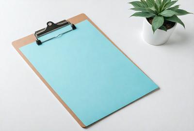 The primary subject of the image is a blue clipboard with a pen attached to it. The clipboard is placed on a white surface, which serves as the setting or background. The visual style of the image is a photo, capturing the clipboard and pen in detail. The dominant colors in the image are blue and white, creating a clean and professional atmosphere.