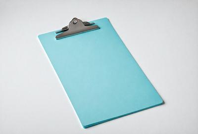 The primary subject of the image is a blue clipboard with a clip holding papers. The setting is a white background, and the visual style is a photo. The dominant colors are blue and white, creating a calm and organized atmosphere.