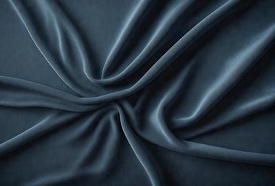 The primary subject of the image is a blue fabric, which is the main object, scene, or focus of the image. The setting or background is a dark blue surface, and the visual style appears to be a photo. The colors and mood of the image are predominantly dark blue, creating a calm and serene atmosphere.
