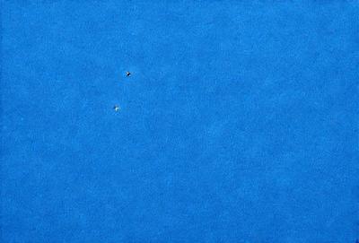 The primary subject of the image is a blue sky with two birds flying in it. The setting is a vast, open sky, and the visual style is a photo. The colors in the image are predominantly blue, creating a calm and serene atmosphere.