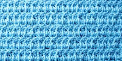 The primary subject of the image is a blue knitted fabric. The setting is a blue background, which creates a contrast with the knitted fabric. The visual style is a close-up of the knitted fabric, showcasing its texture and details. The colors and mood of the image are predominantly blue, giving it a calm and soothing atmosphere.