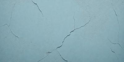 The primary subject of the image is a blue wall with a cracked and peeling surface. The setting is a room with a blue background. The visual style is a close-up of the wall, showcasing the peeling paint and the cracked surface. The colors and mood of the image are predominantly blue, giving it a calm and serene atmosphere.