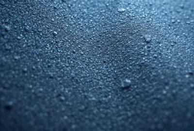 The primary subject of the image is a close-up of a blue surface, possibly a piece of fabric or a wall. The setting appears to be a dark room, with the blue surface being the main focus. The visual style of the image is a close-up, which emphasizes the details of the blue surface. The colors and mood of the image are predominantly dark and moody, with the blue surface being the only noticeable color.