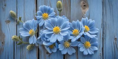 The primary subject of the image is a bouquet of blue flowers, which are the main focus of the scene. The flowers are arranged in a visually appealing manner, creating a sense of beauty and tranquility. The setting is a wooden surface, which serves as the backdrop for the flowers. The visual style of the image is a close-up of the flowers, highlighting their vibrant colors and intricate details. The overall atmosphere of the image is serene and calming, with the blue flowers acting as a so
