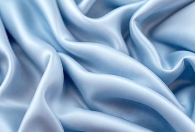 The primary subject of the image is a blue fabric, which appears to be a piece of silk. The setting is a blue background, which complements the blue fabric. The visual style is a close-up of the fabric, showcasing its texture and details. The colors and mood of the image are predominantly blue, creating a calm and serene atmosphere.