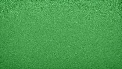 The primary subject of the image is a green background. The setting is a close-up of the green surface, which appears to be a textured or patterned material. The visual style is a photo, and the colors and mood are predominantly green, creating a calm and soothing atmosphere.