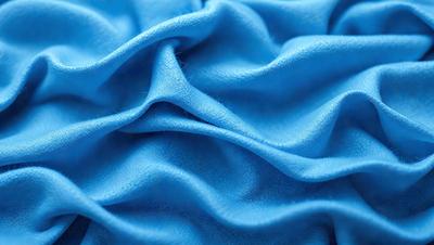 The primary subject of the image is a blue fabric, possibly a piece of cloth or a piece of a blanket. The setting is a close-up view of the fabric, showcasing its texture and details. The visual style appears to be a photo, as it captures the fabric's intricate patterns and textures. The colors and mood of the image are predominantly blue, creating a calm and soothing atmosphere.