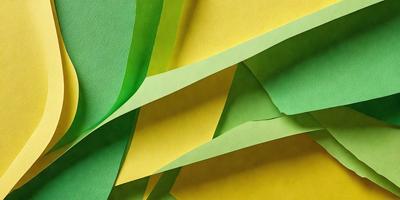 The primary subject of the image is a yellow and green paper, which is the main focus of the image. The setting is a table, and the visual style is a close-up of the paper. The colors and mood of the image are predominantly yellow and green, creating a warm and vibrant atmosphere.