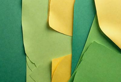 The primary subject of the image is a collection of green and yellow colored paper. The setting is a close-up of the paper, showcasing its texture and color. The visual style is a combination of photo and digital art, as the paper appears to be a blend of both. The colors and mood of the image are vibrant and lively, with the green and yellow paper creating a cheerful atmosphere.