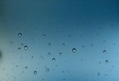 The primary subject of the image is a blue sky filled with water droplets. The setting is a clear, cloudless day, and the visual style is a natural, outdoor scene. The colors and mood of the image are predominantly blue, with the water droplets adding a touch of white and reflecting light. The overall atmosphere is serene and peaceful, as the water droplets create a sense of tranquility and calmness.