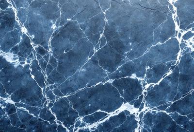 The primary subject of the image is a blue marble wall with a pattern of white and blue veins. The setting is a room with a blue marble wall, and the visual style is a close-up of the marble wall. The colors and mood of the image are predominantly blue, with the white and blue veins adding a touch of contrast and interest to the overall atmosphere.