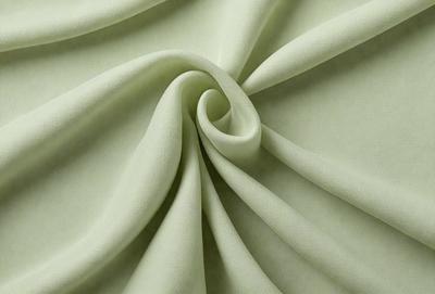 The primary subject of the image is a green fabric, which is the main object, scene, or focus of the image. The setting or background is a white surface, and the visual style is a photo. The colors and mood of the image are predominantly green, giving it a calm and soothing atmosphere.