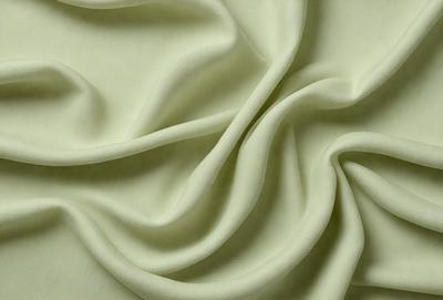 The primary subject of the image is a close-up of a white fabric, possibly a sheet or a piece of clothing. The setting is a white background, which provides a clean and minimalistic appearance. The visual style is a close-up, focusing on the details of the fabric. The colors and mood of the image are predominantly white, giving it a clean and serene atmosphere.
