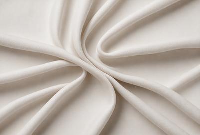 The primary subject of the image is a white sheet of fabric, which is the main object, scene, or focus of the image. The setting or background is a white surface, which provides a clean and minimalistic backdrop for the fabric. The visual style of the image is a close-up of the fabric, showcasing its texture and details. The colors and mood of the image are predominantly white, giving it a clean and serene atmosphere.