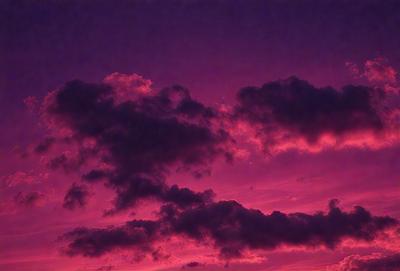 The primary subject of the image is a beautiful sunset with a purple sky. The setting is a cloudy sky, and the visual style is a photo. The colors and mood of the image are predominantly purple, creating a serene and calming atmosphere.