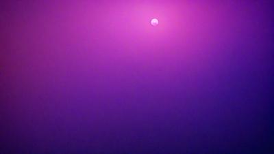 The primary subject of the image is a moon, which is prominently displayed in the sky. The setting is a purple background, which adds a unique and artistic touch to the scene. The visual style of the image is a combination of photo and digital art, creating a captivating and visually appealing representation of the moon. The colors and mood of the image are predominantly purple, which gives it a serene and dreamy atmosphere.