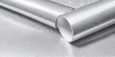 The primary subject of the image is a silver foil or wrapping paper, which is shiny and reflective. The setting is a table, and the visual style appears to be a photo. The colors in the image are predominantly silver, and the overall atmosphere is shiny and reflective.