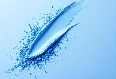 The primary subject of the image is a blue paint splatter, which is the main object, scene, or focus of the image. The setting is a white wall, and the visual style is a photo. The dominant colors are blue and white, creating a calm and serene atmosphere.