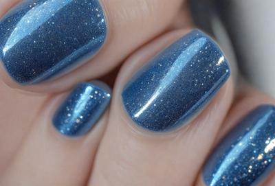 The primary subject of the image is a person's hand holding a bottle of nail polish. The hand is positioned in the foreground, with the bottle of nail polish in the middle of the scene. The background features a blue sky, which adds a sense of depth and contrast to the image. The visual style appears to be a close-up of the hand and the nail polish bottle, emphasizing the details of the scene. The colors and mood of the image are predominantly blue