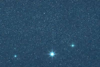 The primary subject of the image is a bright star, which is the main focus of the scene. The setting is a dark, star-filled sky, with the star being the only light source in the image. The visual style is a photo, capturing the beauty of the night sky. The colors and mood of the image are predominantly dark, with the star being the only bright spot, creating a sense of tranquility and wonder.