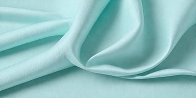 The primary subject of the image is a piece of blue fabric, possibly a sheet or a blanket. The setting is a white surface, which provides a clean and contrasting background. The visual style is a close-up of the fabric, showcasing its texture and color. The dominant colors are blue and white, creating a calm and soothing atmosphere.