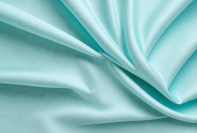 The primary subject of the image is a piece of blue fabric, which is the main object, scene, or focus of the image. The setting or background is a blue surface, which adds to the overall atmosphere of the image. The visual style of the image is a close-up of the fabric, showcasing its texture and details. The colors and mood of the image are predominantly blue, creating a calm and serene atmosphere.