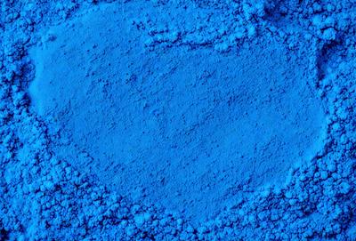 The primary subject of the image is a blue substance, possibly a powder or a liquid, with a heart shape. The setting is a blue background, which adds to the overall visual style. The colors and mood of the image are predominantly blue, creating a calm and serene atmosphere.