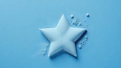 The primary subject of the image is a blue star made of sugar. The setting is a blue background, and the visual style is a close-up of the sugar star. The colors and mood of the image are predominantly blue, creating a calm and serene atmosphere.