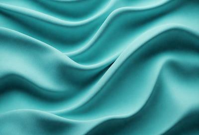 The primary subject of the image is a blue fabric, possibly a piece of cloth or a curtain, with a wavy pattern. The setting is a blue background, which complements the blue fabric. The visual style is a close-up of the fabric, showcasing its texture and pattern. The colors and mood of the image are predominantly blue, creating a calm and serene atmosphere.
