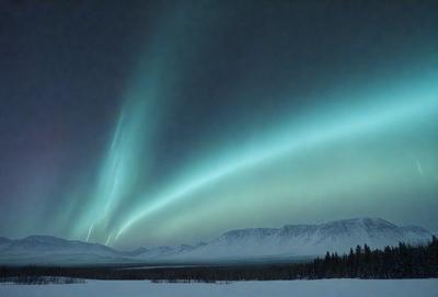 The primary subject of the image is a beautiful, colorful, and vibrant sky. The sky is filled with a variety of colors, creating a stunning visual effect. The setting is a snowy mountain range, with the mountains visible in the background. The visual style of the image is a photo, capturing the natural beauty of the scene. The colors and mood of the image are lively and captivating, making it a captivating and memorable sight.