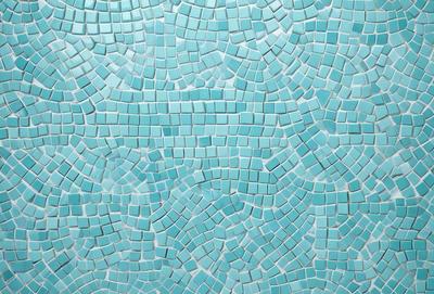 The primary subject of the image is a blue tile wall with a pattern of blue and white tiles. The setting is a room with a blue tile floor, and the visual style is a close-up of the tile wall. The colors and mood of the image are predominantly blue and white, creating a calm and serene atmosphere.