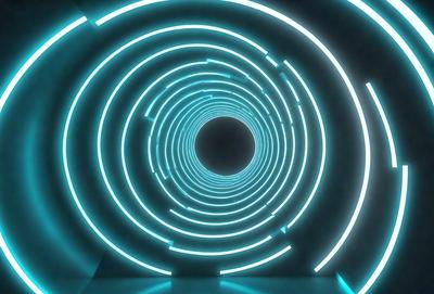 The primary subject of the image is a large, brightly lit tunnel with a blue and white color scheme. The tunnel appears to be a part of a futuristic setting, possibly a space station or a high-tech facility. The tunnel is illuminated by a series of blue and white lights, creating a visually striking and dynamic environment. The overall atmosphere of the image is one of modernity and technological advancement.