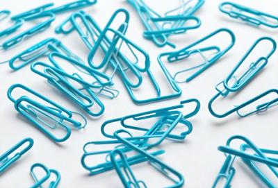 The primary subject of the image is a collection of blue paper clips. The setting is a white background, and the visual style is a close-up of the paper clips. The dominant colors are blue and white, creating a clean and organized appearance.