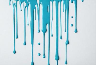 The primary subject of the image is a blue liquid, possibly a paint or a dye, dripping or flowing down a white surface. The setting appears to be a white wall, and the visual style is a close-up of the dripping liquid. The colors and mood of the image are predominantly blue, creating a calm and serene atmosphere.