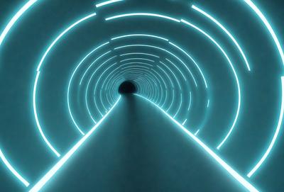 The primary subject of the image is a tunnel with a blue light illuminating it. The tunnel appears to be a long, narrow passage with a blue glow emanating from it. The setting is a dark environment, and the visual style is a digital art or illustration. The colors and mood of the image are predominantly blue, creating a sense of depth and mystery.