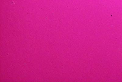 The primary subject of the image is a pink background with a few black dots scattered across it. The setting appears to be a simple, flat surface, and the visual style is a close-up of the pink background. The colors and mood of the image are predominantly pink, with the black dots adding a touch of contrast and interest to the overall composition.