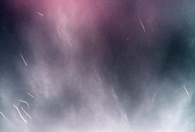 The primary subject of the image is a cloudy sky filled with stars. The setting is a dark, cloudy background, and the visual style is a photo. The colors and mood of the image are dark and moody, with the stars and clouds creating a dramatic and atmospheric scene.