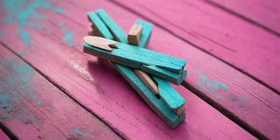 The primary subject of the image is a wooden clothespin with a blue and green color scheme. The setting is a pink table, which serves as the background for the scene. The visual style of the image is a close-up of the wooden clothespin, showcasing its unique color combination. The colors and mood of the image are vibrant and cheerful, with the pink table adding a touch of warmth to the scene.