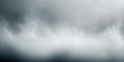 The primary subject of the image is a cloudy sky. The setting is a dark, cloudy day with a gloomy atmosphere. The visual style is a photo of the sky, showcasing the clouds and their patterns. The colors and mood are predominantly dark and moody, with the clouds being the main focus of the image.
