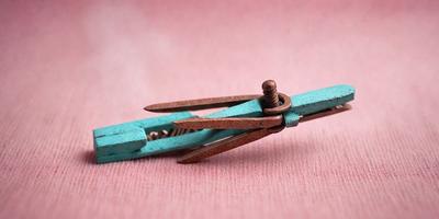 The primary subject of the image is a pair of scissors with a wooden handle. The scissors are placed on a pink surface, which serves as the setting or background. The visual style of the image is a photo, capturing the details of the scissors and the pink surface. The colors in the image are predominantly pink, creating a warm and inviting atmosphere.