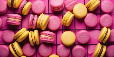 The primary subject of the image is a close-up of a pink and yellow macaron, which is placed on a pink surface. The setting is a pink grid, and the visual style appears to be a photo. The dominant colors in the image are pink and yellow, creating a cheerful and vibrant atmosphere.