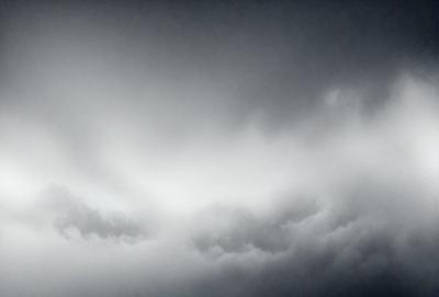 The primary subject of the image is a cloudy sky. The setting is a dark, cloudy day with a gloomy atmosphere. The visual style is a photo, capturing the cloudy sky in its natural environment. The colors and mood are predominantly dark and moody, with the clouds being the main focus of the image.