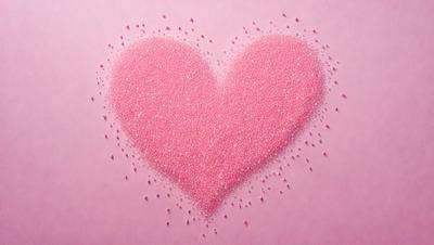 The primary subject of the image is a heart-shaped pink object, which appears to be made of glitter or confetti. The heart is placed on a pink surface, which could be a table or a wall. The visual style of the image is a close-up of the heart, emphasizing its shape and texture. The colors and mood of the image are predominantly pink, creating a warm and inviting atmosphere.