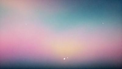 The primary subject of the image is a colorful sky with a mix of pink, blue, and purple hues. The setting is a cloudy day, and the visual style appears to be a combination of a photo and digital art. The colors and mood of the image are vibrant and lively, creating a sense of wonder and beauty.