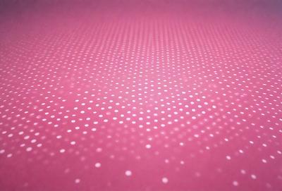 The primary subject of the image is a close-up of a pink surface with a pattern of white dots. The setting appears to be a room with a pink background. The visual style is a close-up of the pink surface, which gives a sense of depth and texture. The colors and mood of the image are predominantly pink and white, creating a warm and inviting atmosphere.
