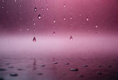 The primary subject of the image is a purple sky with rain falling. The setting is a pink sky, and the visual style is a photo. The colors and mood of the image are predominantly purple and pink, creating a serene and calming atmosphere.