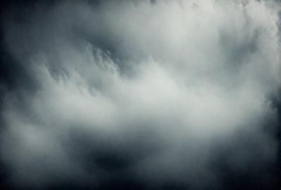 The primary subject of the image is a cloudy sky. The setting is a dark, cloudy day with a stormy atmosphere. The visual style is a photo of the cloudy sky. The colors and mood are dark and moody, with the clouds creating a dramatic and ominous backdrop.