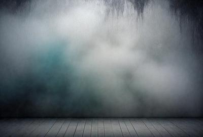 The primary subject of the image is a large, white cloud that is floating in the sky. The setting is a room with a wooden floor, and the visual style appears to be a combination of a photo and digital art. The cloud is the main focus of the image, and it creates a dramatic and moody atmosphere.