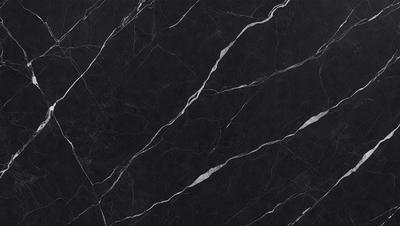 The primary subject of the image is a black marble countertop. The setting is a kitchen, with the countertop being the main focus of the scene. The visual style is a close-up of the marble countertop, showcasing its texture and pattern. The colors and mood of the image are predominantly dark, with the black marble providing a striking contrast against the surrounding environment.